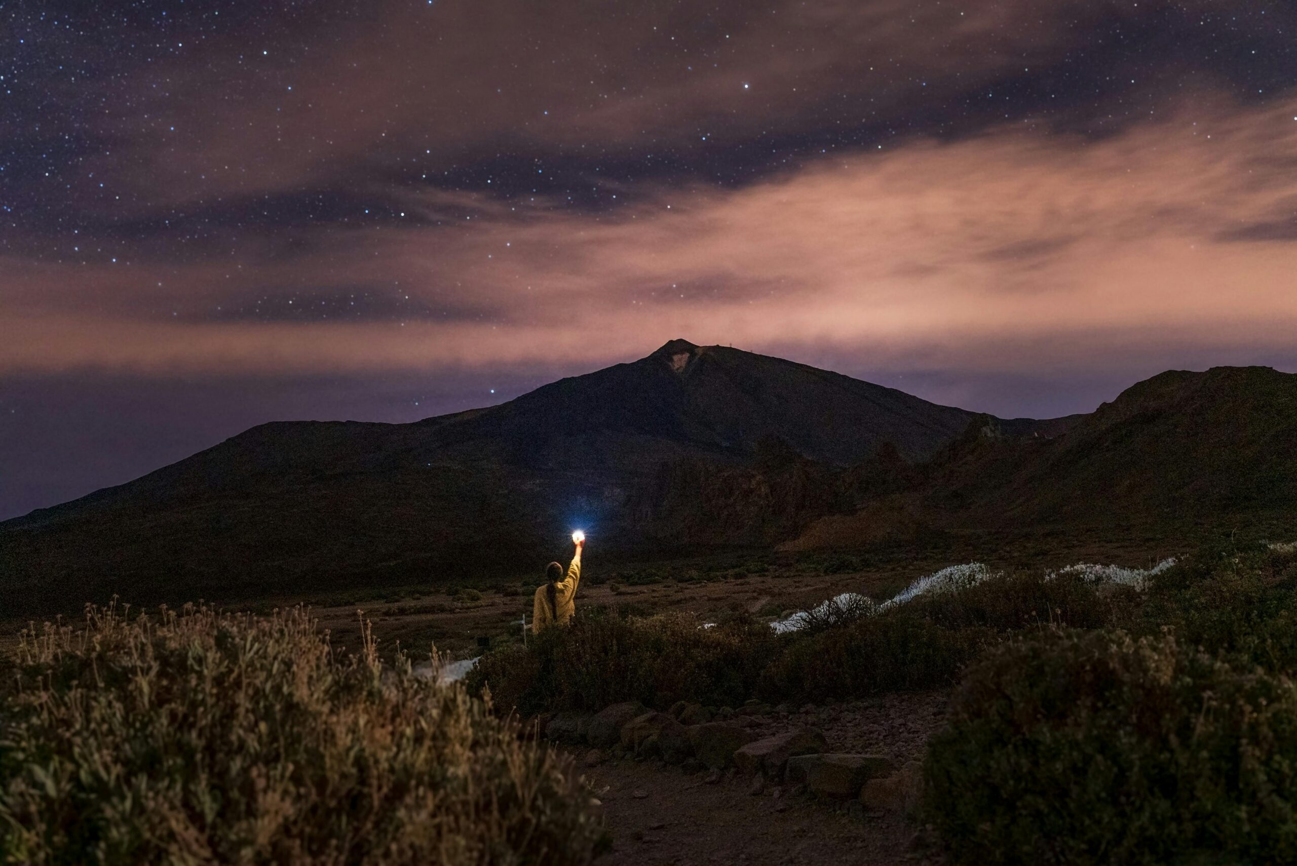 Woman holding flashlight under starry sky in Santiago del Teide, Spain.